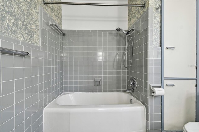 3001 Bay Shore Cir, Sarasota, FL 34234 - full bath featuring washtub / shower combination, tile walls, toilet, and wallpapered walls