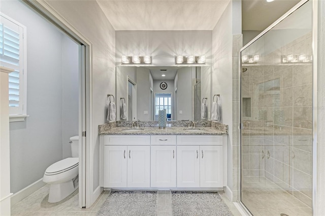 13609 Messina Loop Unit 104, Bradenton, FL 34211 - bathroom featuring toilet, a shower stall, double vanity, tile patterned floors, and baseboards