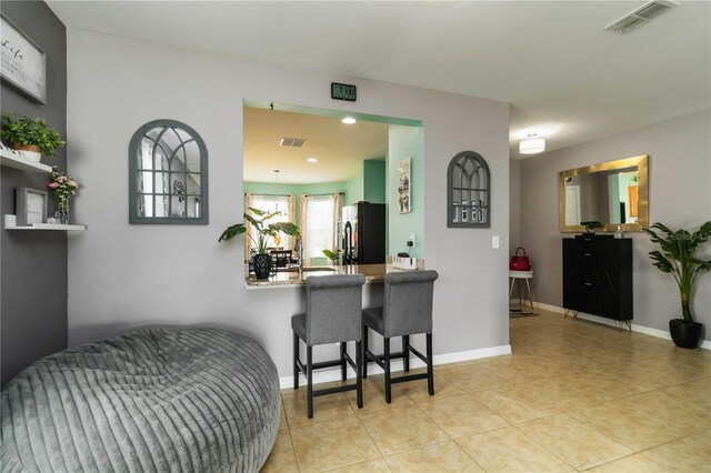 8937 Excelsior Loop, Venice, FL 34293 - kitchen with freestanding refrigerator, light tile patterned flooring, a breakfast bar, baseboards, and recessed lighting