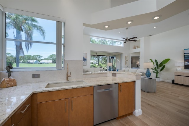 7952 Hampton Ct, University Park, FL 34201 - kitchen with stainless steel dishwasher, a sink, open floor plan, brown cabinets, and light stone counters