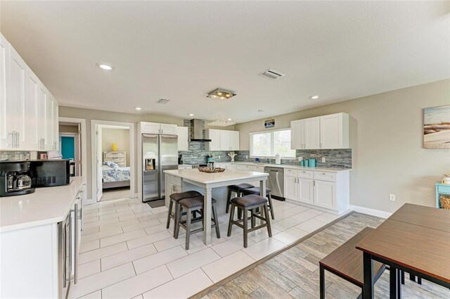 3903 Bayside Dr, Bradenton, FL 34210 - kitchen with appliances with stainless steel finishes, wall chimney range hood, a kitchen breakfast bar, tasteful backsplash, and recessed lighting
