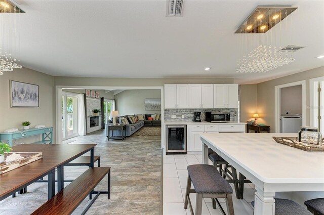 3903 Bayside Dr, Bradenton, FL 34210 - kitchen with wine cooler, stainless steel microwave, white cabinets, decorative backsplash, and light countertops