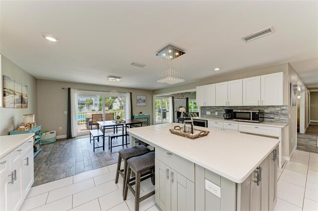3903 Bayside Dr, Bradenton, FL 34210 - kitchen featuring stainless steel microwave, light countertops, white cabinetry, a kitchen island, and recessed lighting