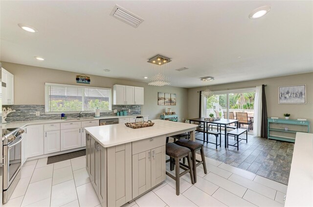 3903 Bayside Dr, Bradenton, FL 34210 - kitchen with stainless steel appliances, light countertops, tasteful backsplash, a kitchen island, and white cabinets