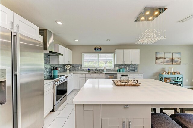 3903 Bayside Dr, Bradenton, FL 34210 - kitchen featuring appliances with stainless steel finishes, wall chimney range hood, a sink, backsplash, and a kitchen island