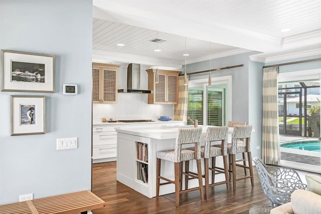 510 Wedge Ln, Longboat Key, FL 34228 - kitchen with wall chimney range hood, a kitchen bar, dark wood-style floors, ornamental molding, and light countertops