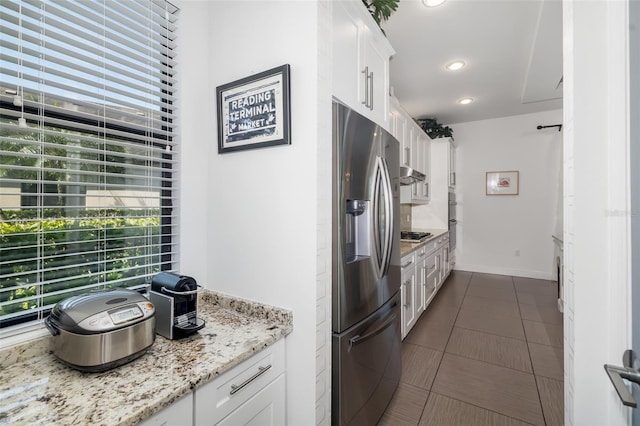 826 Honeyflower Loop, Bradenton, FL 34212 - kitchen with stainless steel appliances, white cabinets, under cabinet range hood, light stone countertops, and dark tile patterned floors