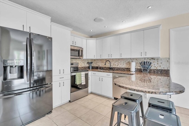 6731 Washington Pl, Bradenton, FL 34207 - kitchen featuring stainless steel appliances, a peninsula, a sink, light tile patterned flooring, and backsplash