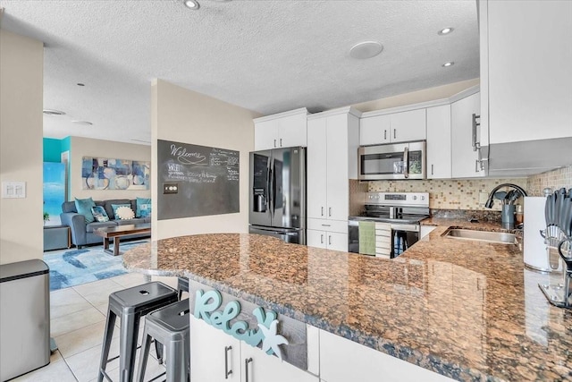 6731 Washington Pl, Bradenton, FL 34207 - kitchen with stainless steel appliances, a sink, dark stone counters, a peninsula, and white cabinetry