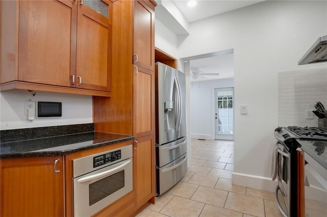 480 28th Ave N, Saint Petersburg, FL 33704 - kitchen with stainless steel appliances, light tile patterned floors, a ceiling fan, dark stone countertops, and brown cabinetry