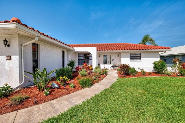 74 Windsor Dr, Englewood, FL 34223 - mediterranean / spanish home featuring stucco siding, a front lawn, and a tile roof