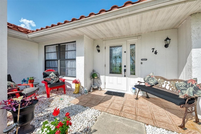 74 Windsor Dr, Englewood, FL 34223 - property entrance featuring stucco siding, a porch, and a tile roof