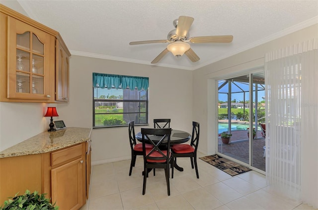 74 Windsor Dr, Englewood, FL 34223 - dining area featuring a ceiling fan, plenty of natural light, ornamental molding, light tile patterned flooring, and a textured ceiling