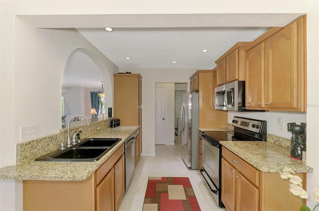 74 Windsor Dr, Englewood, FL 34223 - kitchen with stainless steel appliances, light stone counters, light tile patterned floors, recessed lighting, and arched walkways