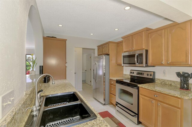 74 Windsor Dr, Englewood, FL 34223 - kitchen featuring stainless steel appliances, recessed lighting, light stone counters, a textured ceiling, and light brown cabinetry