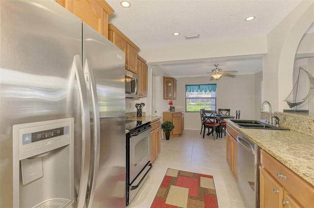 74 Windsor Dr, Englewood, FL 34223 - kitchen with appliances with stainless steel finishes, light tile patterned floors, a ceiling fan, light stone counters, and brown cabinets