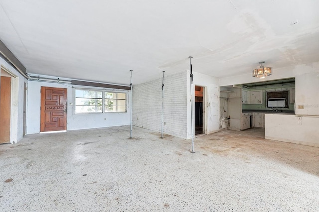 9300 Gulf Blvd, St Pete Beach, FL 33706 - unfurnished living room featuring brick wall and a chandelier