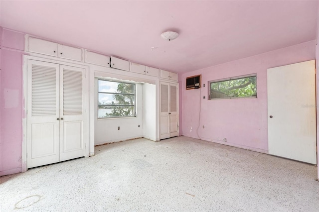 9300 Gulf Blvd, St Pete Beach, FL 33706 - unfurnished bedroom featuring multiple windows, speckle patterned floor, and multiple closets