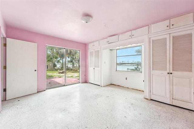 9300 Gulf Blvd, St Pete Beach, FL 33706 - unfurnished bedroom with access to exterior, multiple windows, multiple closets, and speckled floor