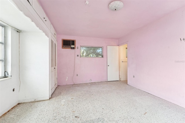 9300 Gulf Blvd, St Pete Beach, FL 33706 - empty room with plenty of natural light, speckled floor, and a wall mounted air conditioner