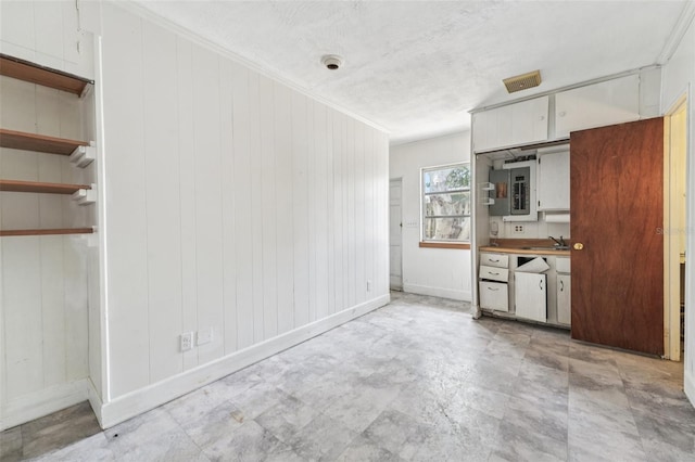 9300 Gulf Blvd, St Pete Beach, FL 33706 - kitchen with baseboards, white cabinets, crown molding, wood walls, and a sink