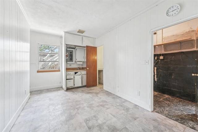 9300 Gulf Blvd, St Pete Beach, FL 33706 - unfurnished living room with baseboards, a sink, wooden walls, and ornamental molding