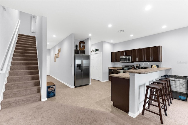 4644 Vignette Way, Sarasota, FL 34240 - kitchen with stainless steel appliances, a breakfast bar, dark brown cabinets, recessed lighting, and a peninsula
