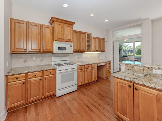 673 Crane Prairie Way, Osprey, FL 34229 - kitchen featuring white appliances, light wood-style flooring, decorative backsplash, light stone countertops, and glass insert cabinets