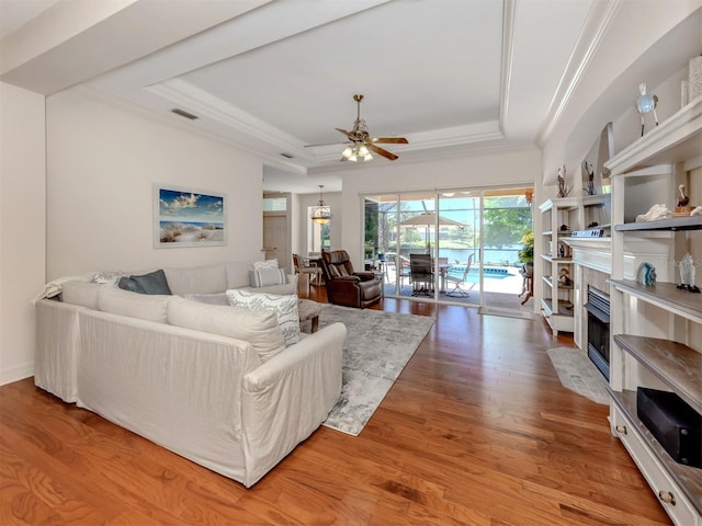 673 Crane Prairie Way, Osprey, FL 34229 - living room with a tray ceiling, a ceiling fan, wood finished floors, crown molding, and a fireplace