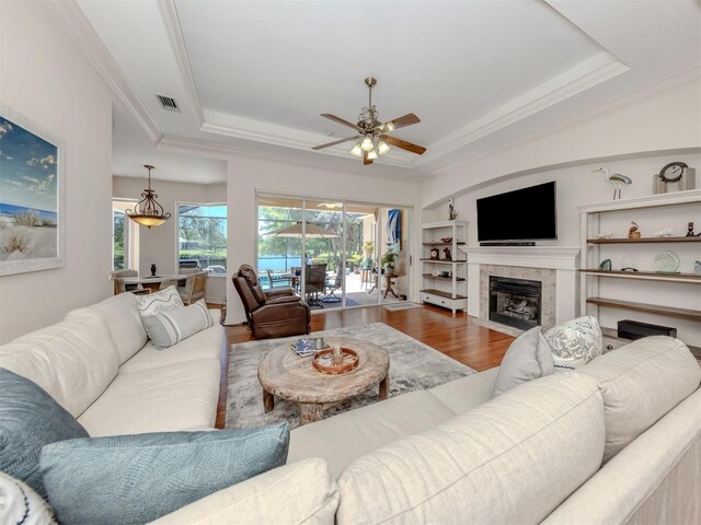 673 Crane Prairie Way, Osprey, FL 34229 - living area with a raised ceiling, ceiling fan, crown molding, wood finished floors, and a tiled fireplace