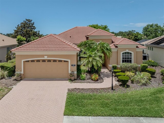 673 Crane Prairie Way, Osprey, FL 34229 - mediterranean / spanish house featuring stucco siding, a garage, decorative driveway, and a tile roof
