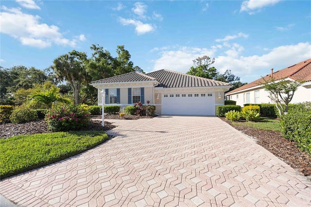 5018 Hanging Moss Ln, Sarasota, FL 34238 - mediterranean / spanish home with an attached garage, decorative driveway, a tile roof, and stucco siding