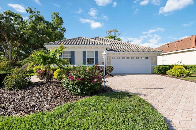 5018 Hanging Moss Ln, Sarasota, FL 34238 - mediterranean / spanish-style house with a tile roof, a garage, decorative driveway, and stucco siding