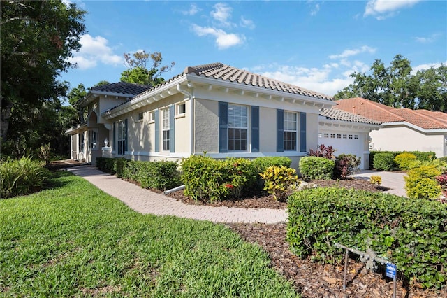 5018 Hanging Moss Ln, Sarasota, FL 34238 - view of front of house with an attached garage, a tile roof, stucco siding, a front yard, and driveway