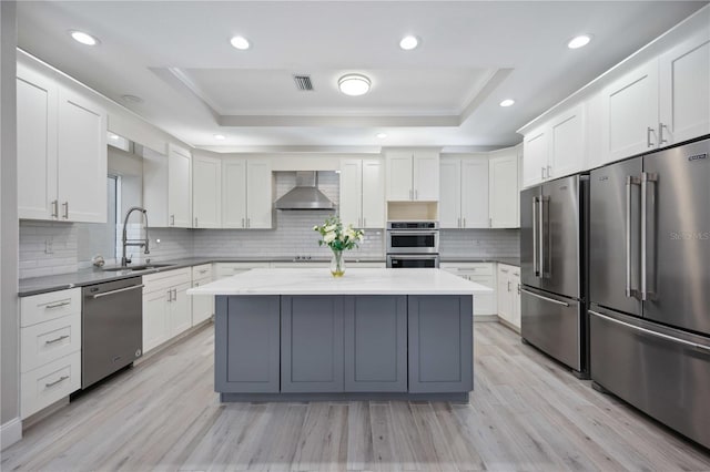 5018 Hanging Moss Ln, Sarasota, FL 34238 - kitchen with stainless steel appliances, a raised ceiling, wall chimney exhaust hood, a center island, and backsplash