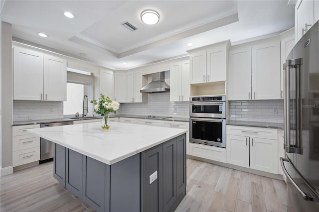 5018 Hanging Moss Ln, Sarasota, FL 34238 - kitchen with appliances with stainless steel finishes, a raised ceiling, wall chimney range hood, crown molding, and backsplash