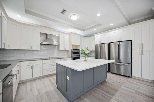 5018 Hanging Moss Ln, Sarasota, FL 34238 - kitchen with stainless steel appliances, wall chimney range hood, a tray ceiling, crown molding, and tasteful backsplash