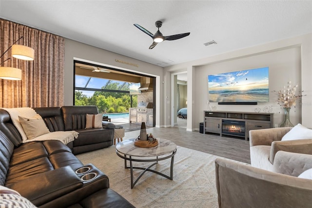 15316 Shady Palms Ln, Nokomis, FL 34275 - living room with a ceiling fan, a glass covered fireplace, and wood finished floors