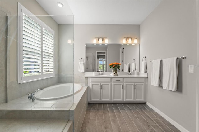 15316 Shady Palms Ln, Nokomis, FL 34275 - bathroom featuring double vanity, a garden tub, and wood finished floors