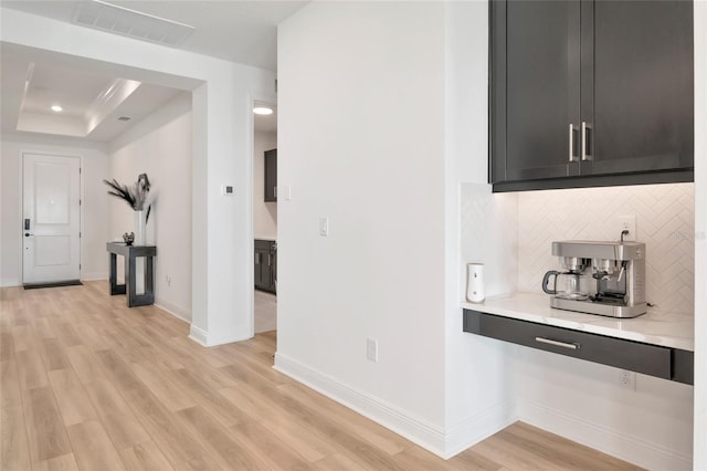 17333 Savory Mist Cir, Bradenton, FL 34211 - kitchen with light countertops, tasteful backsplash, light wood finished floors, a tray ceiling, and baseboards