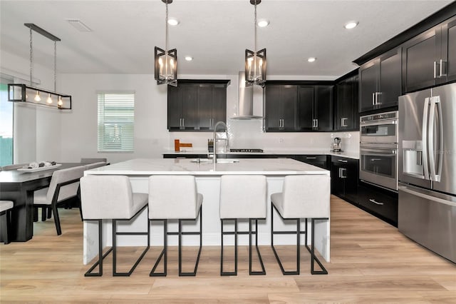 17333 Savory Mist Cir, Bradenton, FL 34211 - kitchen with appliances with stainless steel finishes, dark cabinets, light wood finished floors, a kitchen breakfast bar, and recessed lighting