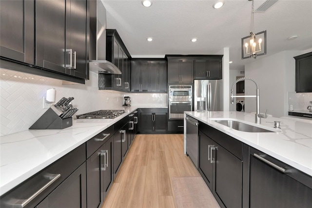 17333 Savory Mist Cir, Bradenton, FL 34211 - kitchen with stainless steel appliances, a sink, light wood finished floors, hanging light fixtures, and decorative backsplash