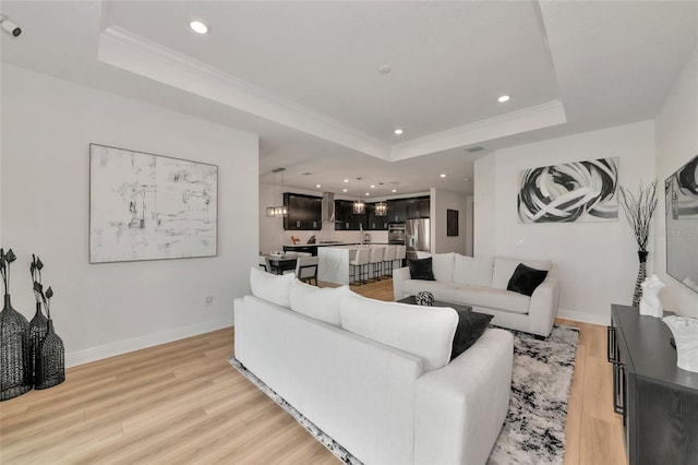17333 Savory Mist Cir, Bradenton, FL 34211 - living room featuring a tray ceiling, light wood-style flooring, recessed lighting, crown molding, and baseboards