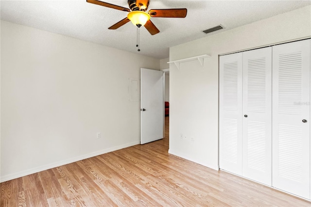 5500 Longwood Run Blvd Unit 203, Sarasota, FL 34243 - unfurnished bedroom featuring light wood-style flooring, a closet, a ceiling fan, and a textured ceiling