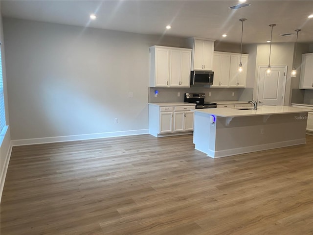 1710 Summer Rose Dr, Mount Dora, FL 32757 - kitchen featuring appliances with stainless steel finishes, white cabinets, a kitchen island with sink, light wood-type flooring, and recessed lighting