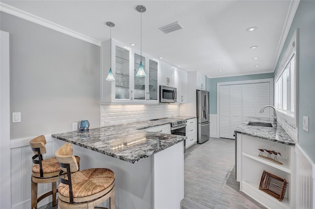 139 Vista Hermosa Cir, Sarasota, FL 34242 - kitchen with appliances with stainless steel finishes, crown molding, stone counters, a peninsula, and glass insert cabinets