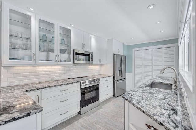 139 Vista Hermosa Cir, Sarasota, FL 34242 - kitchen featuring stainless steel appliances, ornamental molding, white cabinets, light stone counters, and glass insert cabinets