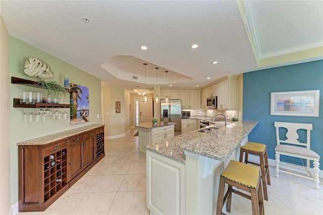 7820 34th Ave W Unit 102, Bradenton, FL 34209 - kitchen featuring a tray ceiling, appliances with stainless steel finishes, a textured ceiling, light tile patterned flooring, and a peninsula