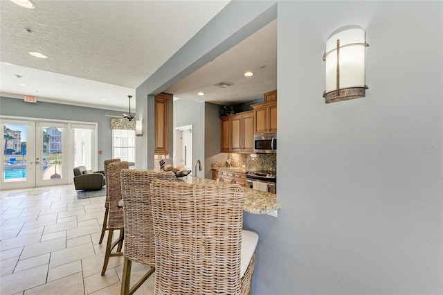 7820 34th Ave W Unit 102, Bradenton, FL 34209 - kitchen featuring appliances with stainless steel finishes, brown cabinetry, recessed lighting, tasteful backsplash, and a textured ceiling