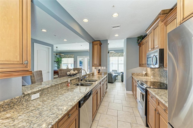 7820 34th Ave W Unit 102, Bradenton, FL 34209 - kitchen featuring stainless steel appliances, light stone counters, recessed lighting, brown cabinets, and a ceiling fan